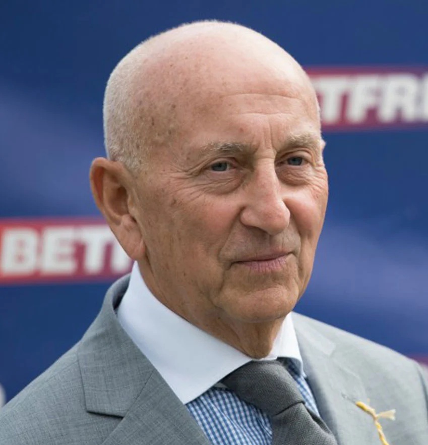 Elderly man in suit at outdoor event.