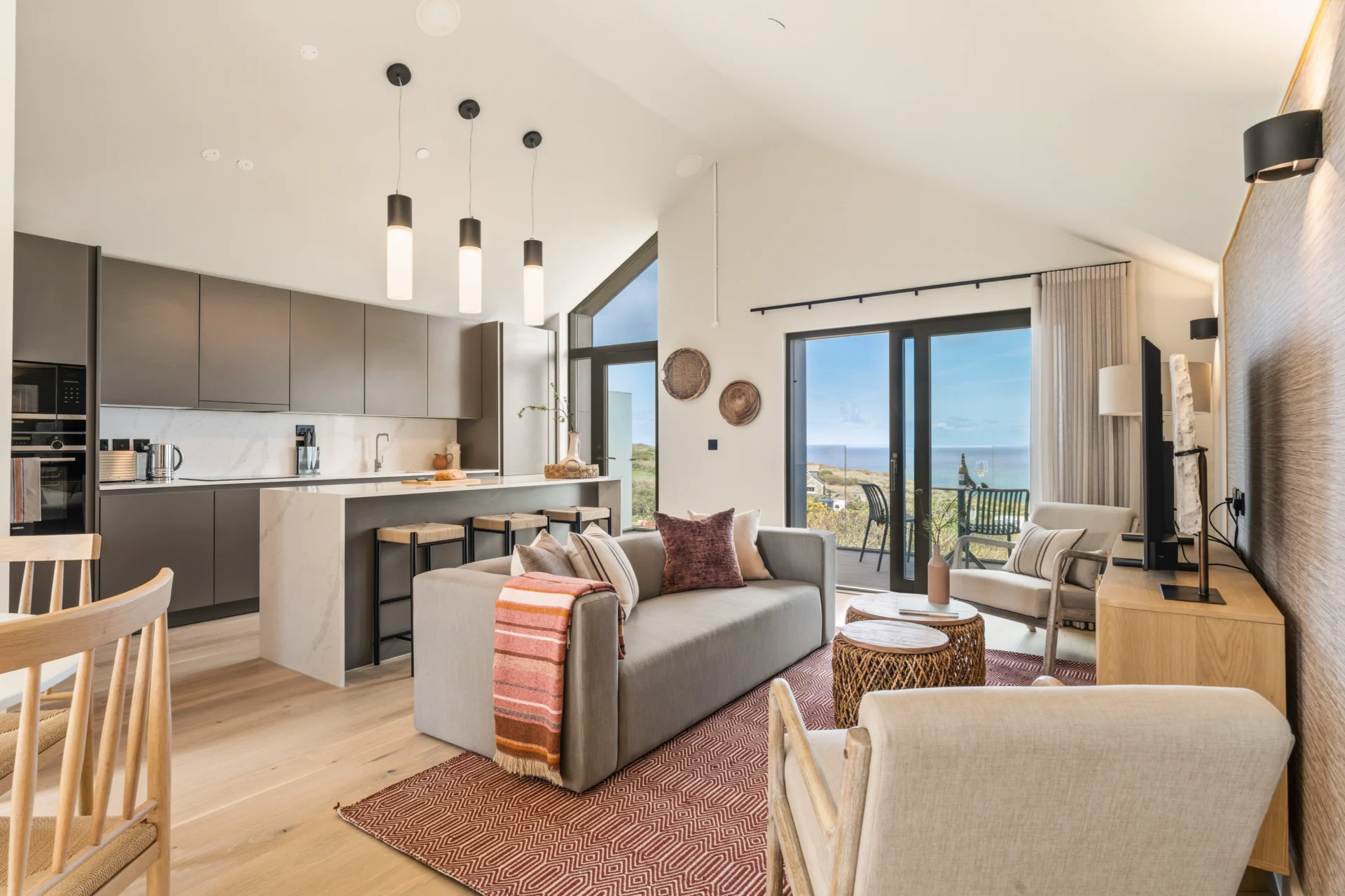 Modern living room with open kitchen and ocean view.