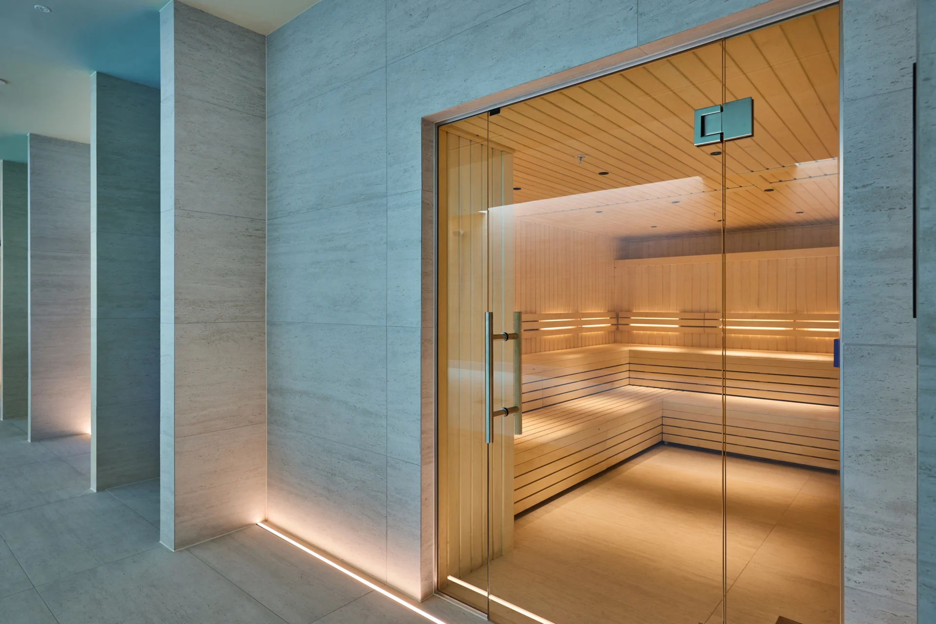 Modern sauna room with wooden interior and glass door.