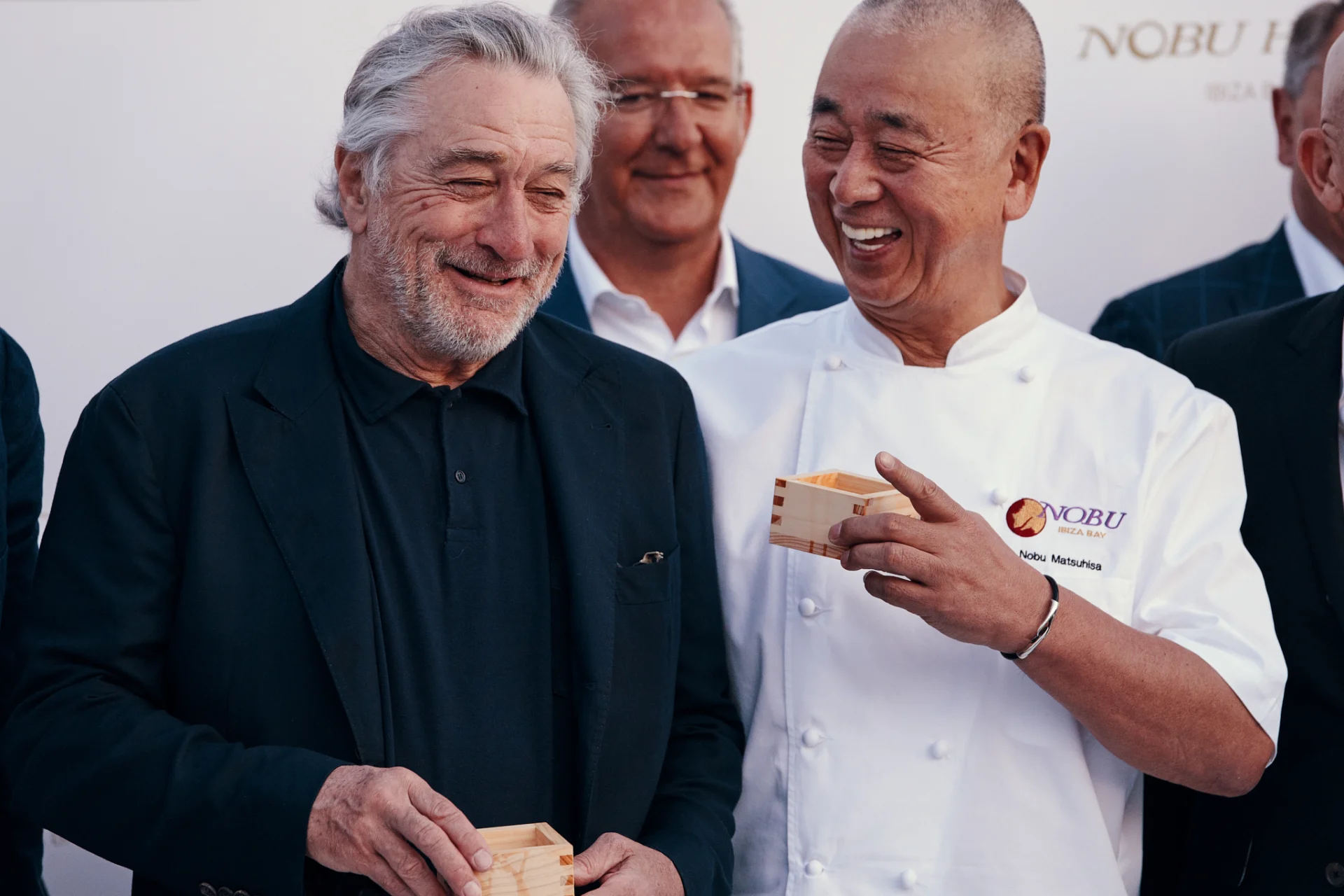 Two men smiling and holding wooden boxes.