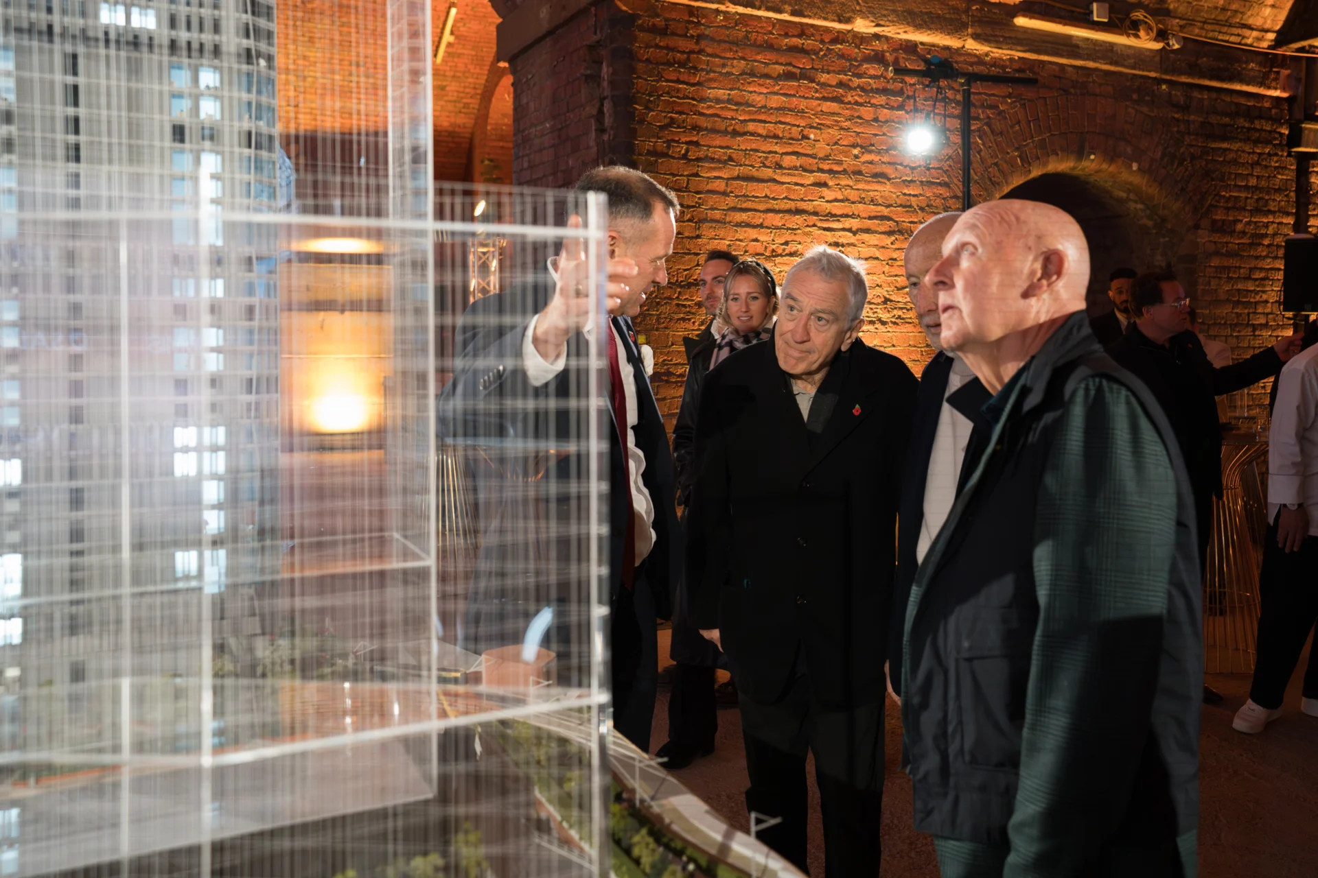 People examining architectural model at exhibition.