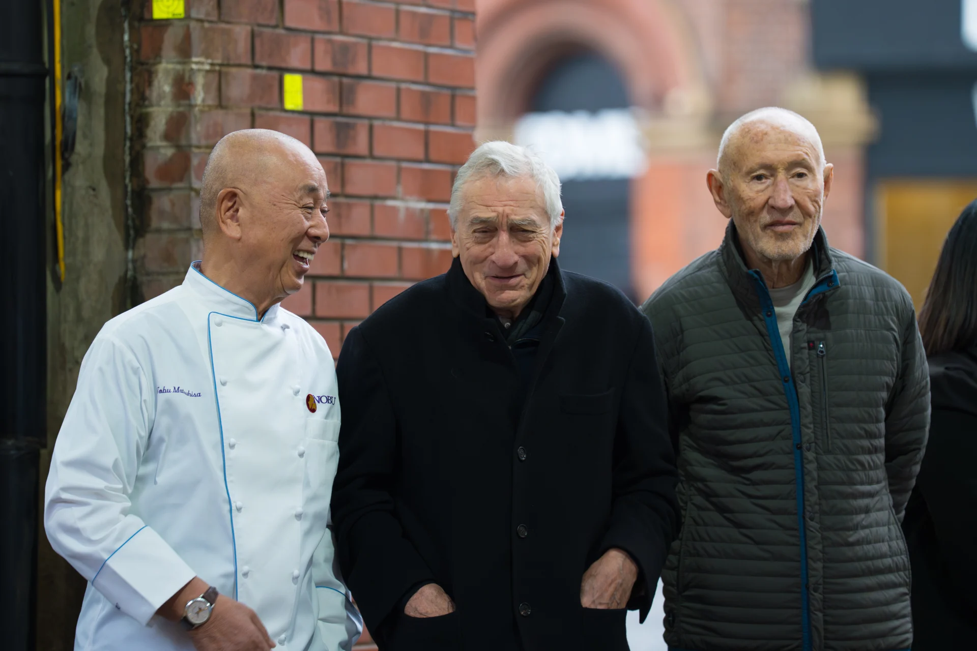 Three men smiling outdoors.