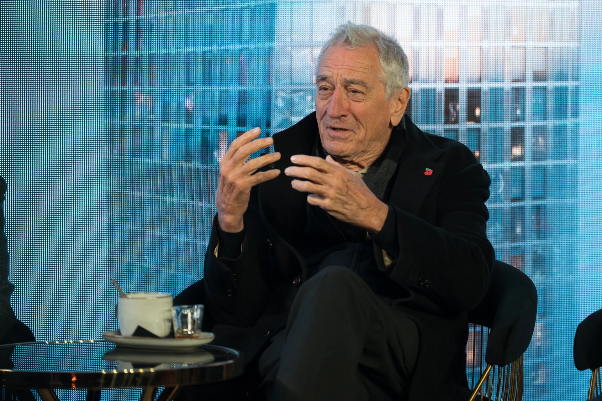 Elderly man talking with hand gestures indoors.
