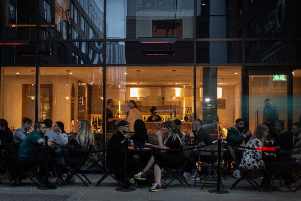 Outdoor cafe scene at night with people dining.