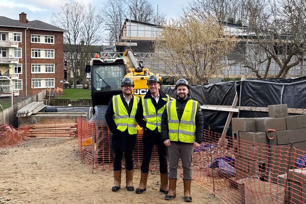Three workers at a construction site with equipment.