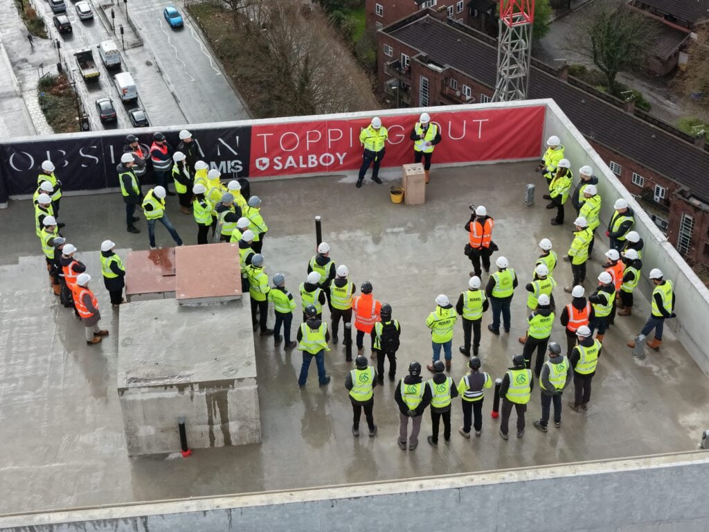 Construction workers gather on rooftop safety meeting.