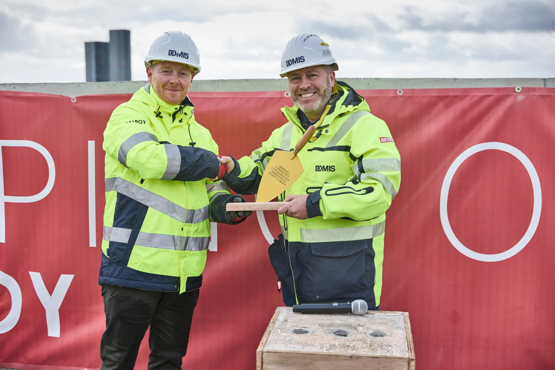Two construction workers shaking hands at event.