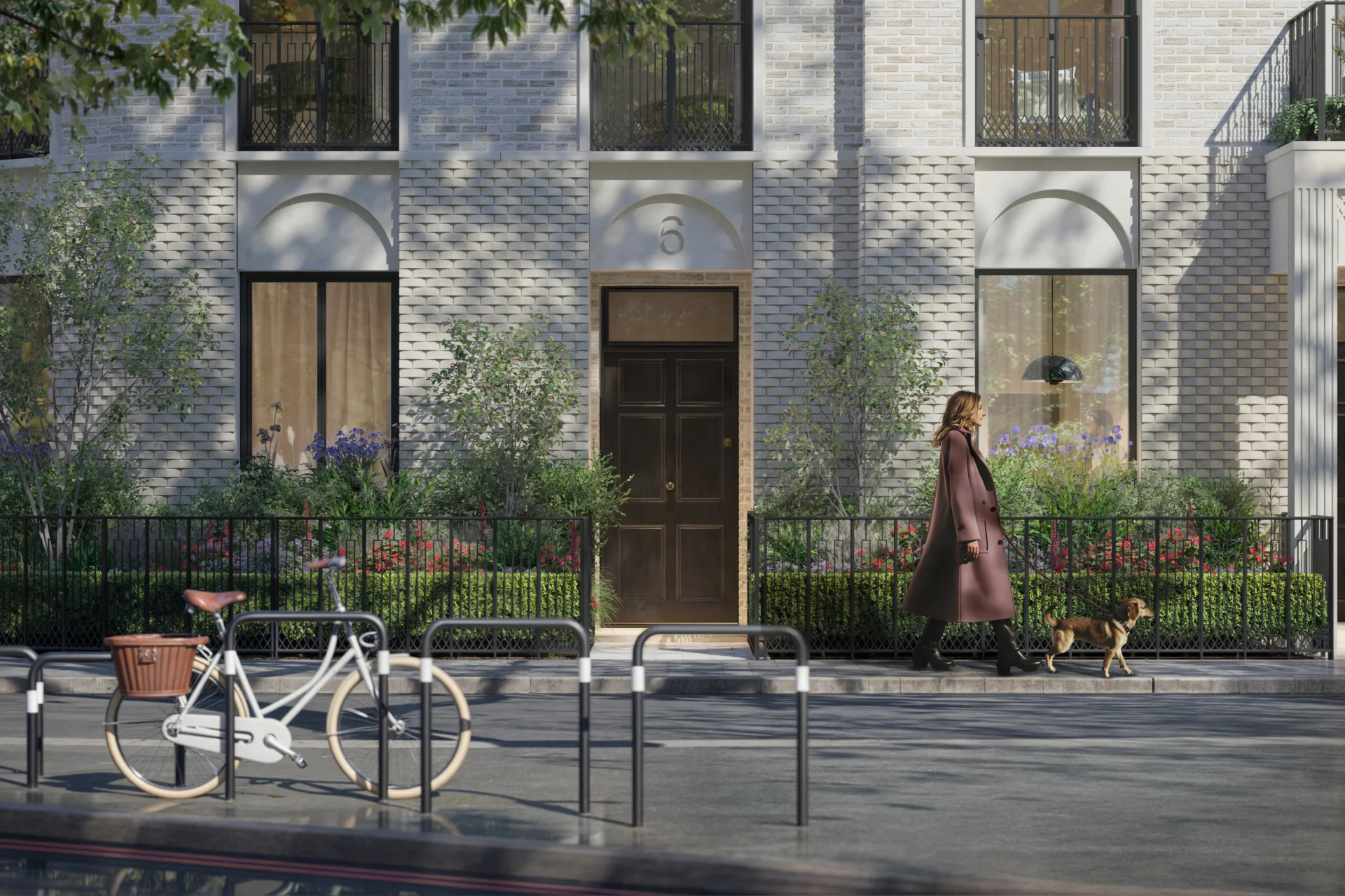 Woman walking dog past brick townhouse with bicycle.